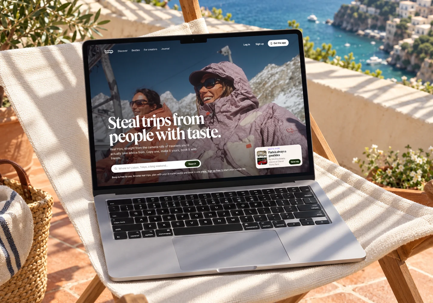 Boop homepage on a MacBook resting on a canvas chair on a coastal terrace.